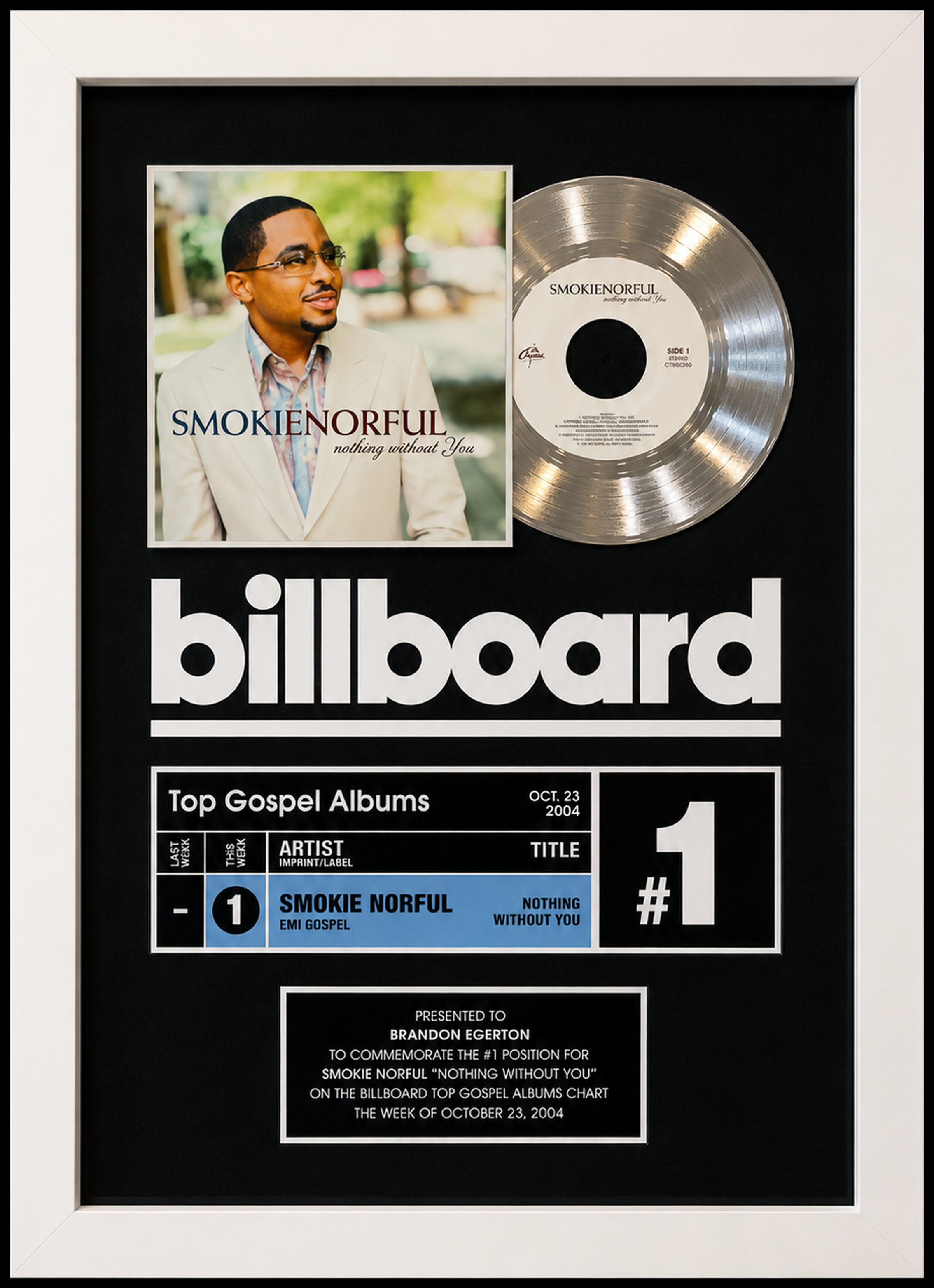 A framed Billboard chart plaque featuring Smokie Norful's gospel album "Nothing Without You" at the number one spot for the week of October 23, 2004, with a platinum record and an album cover showing Smokie Norful. Presented to Brandon Egerton.