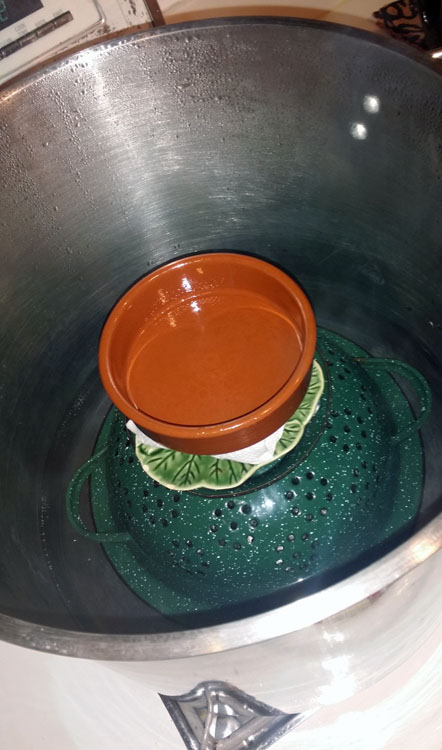 My kitchen rig. Upturned colander as steamer, our least-favorite ceramic plates as weights to hold the paper-rolled skeins in place. I have an electric water boiler continuously ready with the next batch of boiling water so the steaming isn't interrupted.