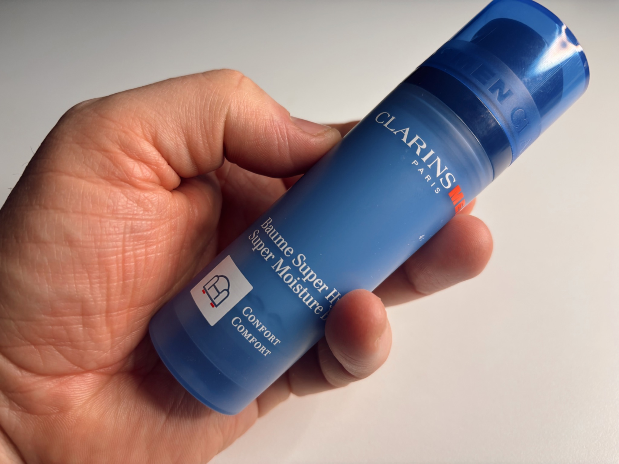 Clarins Men Super Moisture Balm held in hand showing blue bottle design, tested as a daily moisturiser for men over 40