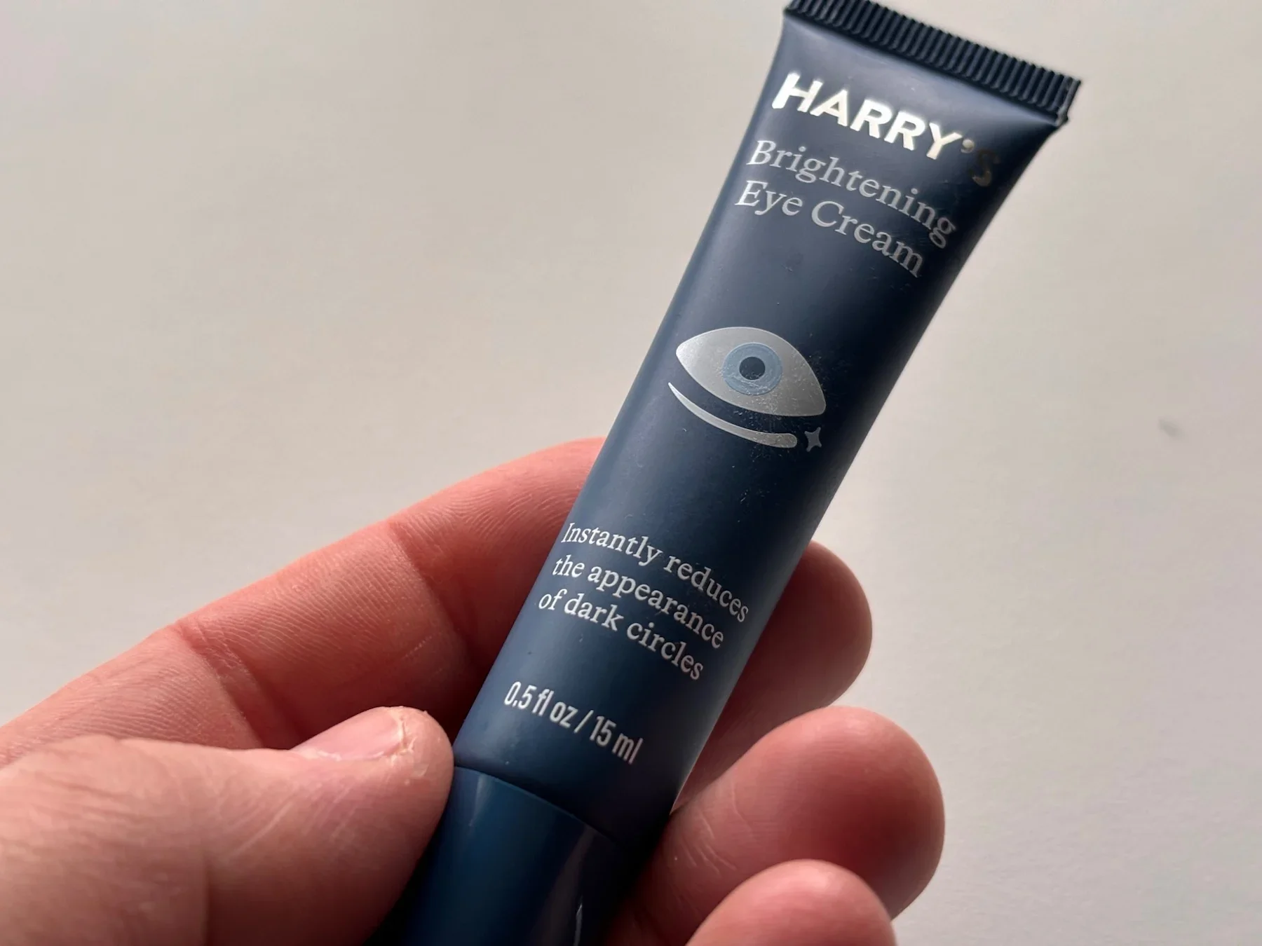 Jerome holding a tube of Harry's Brightening Eye Cream for a real-world budget review.