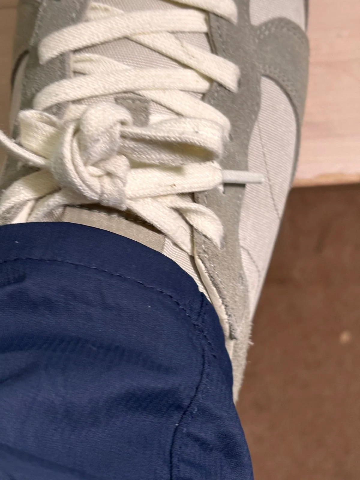 Close-up detail of the hem and fabric of Tailor Vintage navy slim fit chinos worn with trainers.