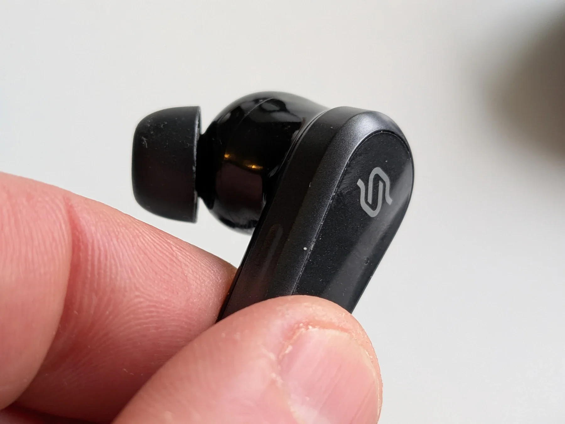 Close-up side profile of a single Edifier STAX Spirit S10 earbud held between fingers