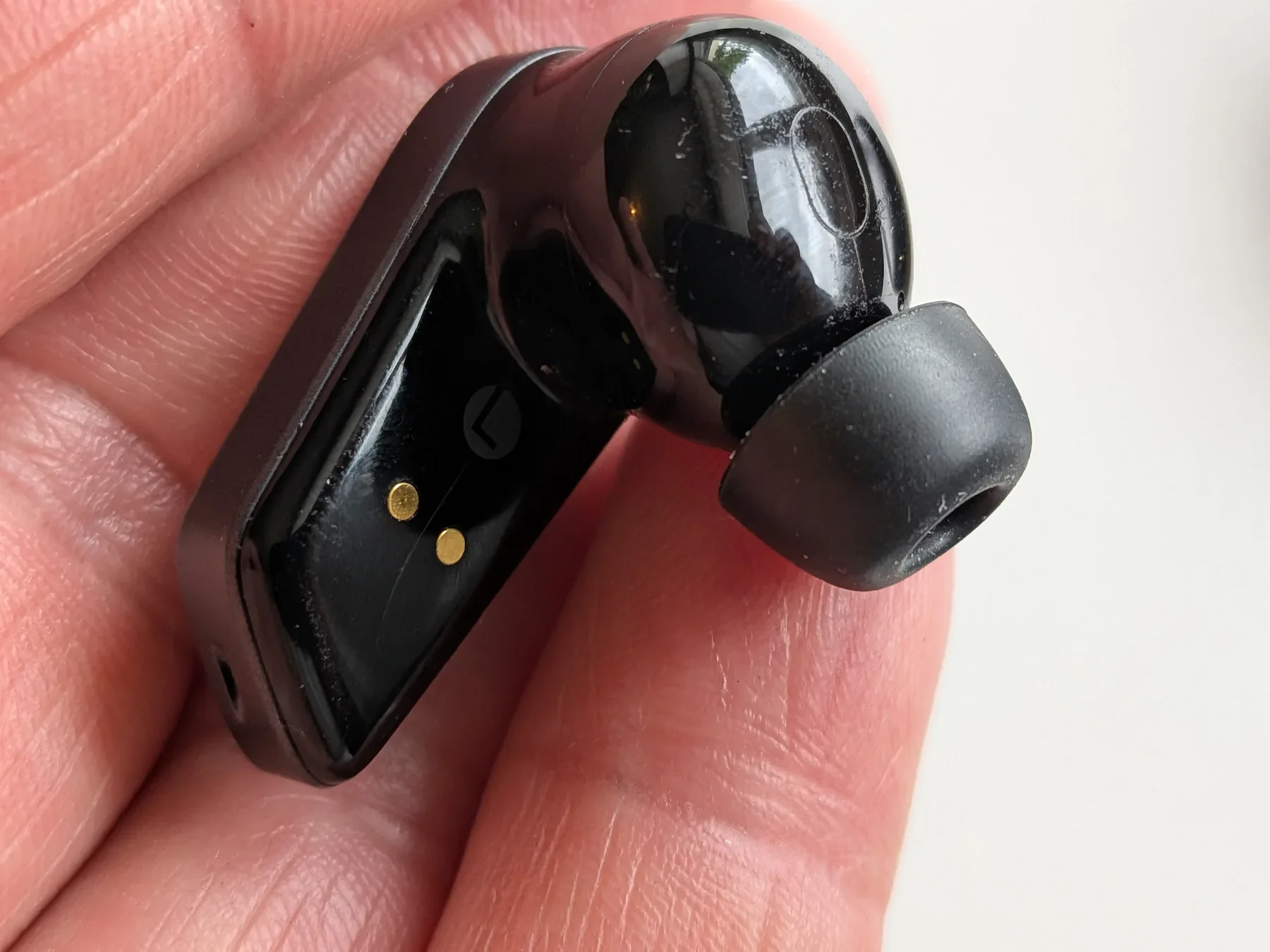 Close-up of the inner side of an Edifier STAX Spirit S10 earbud showing charging pins and ear tip
