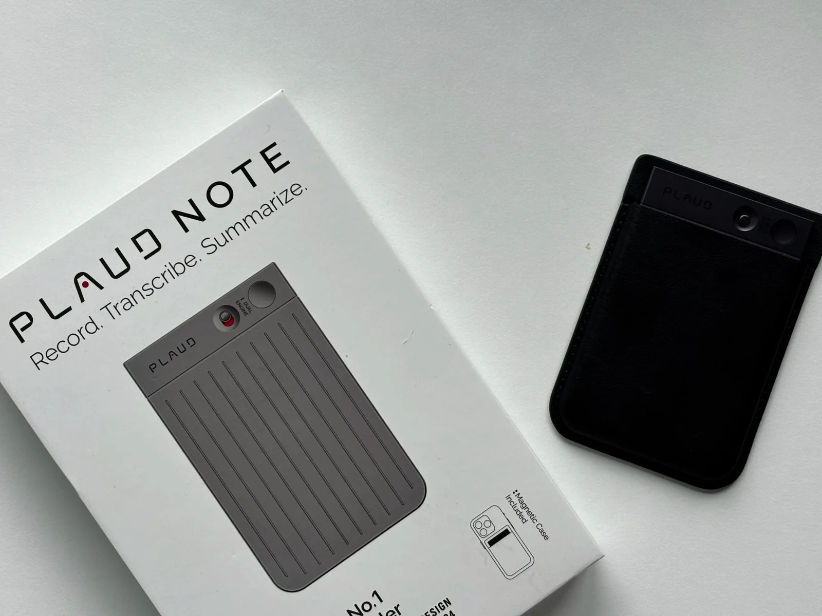 Plaud Note retail box next to the device in its magnetic case on a white background
