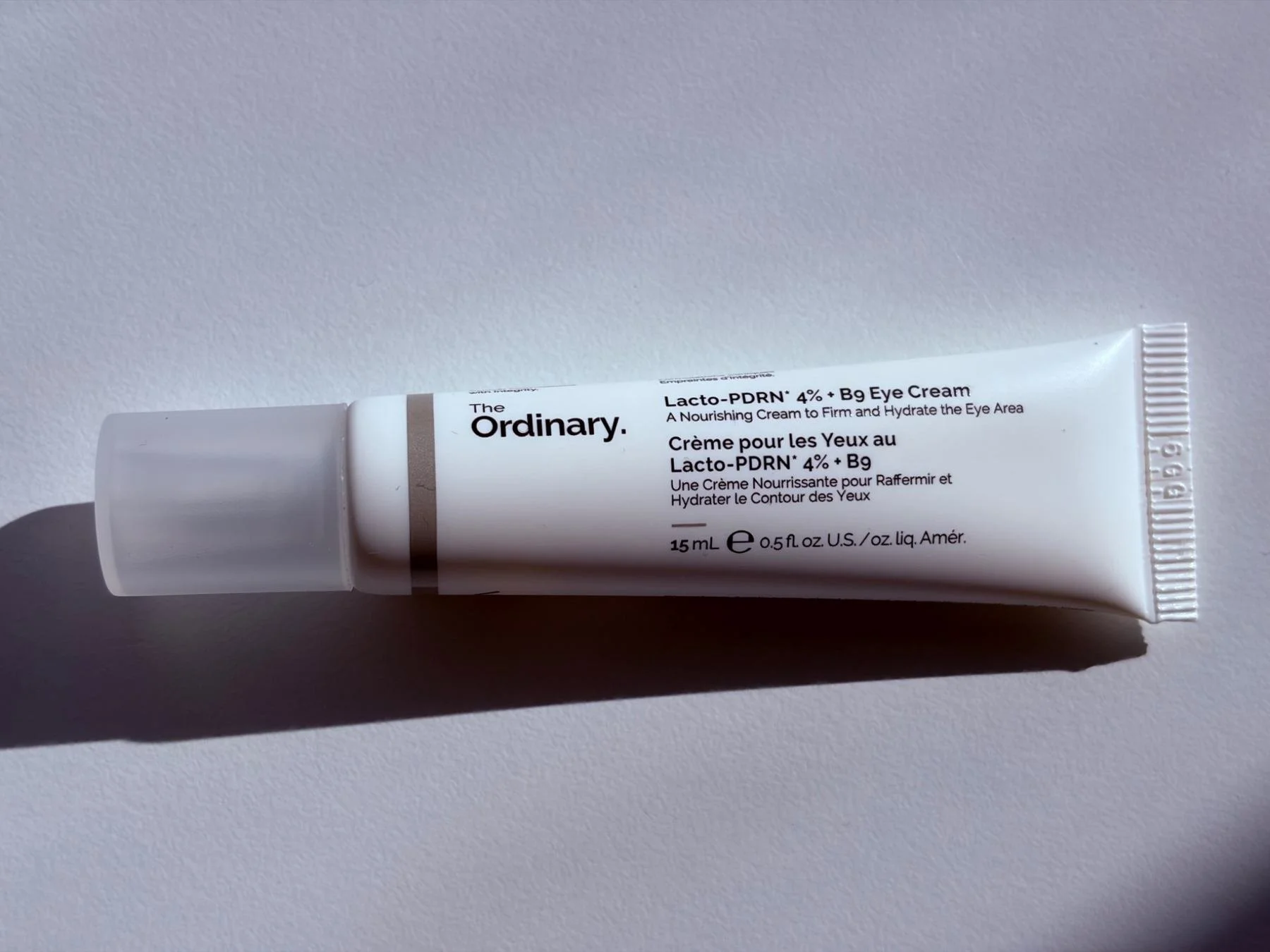 Close-up of The Ordinary Lacto-PDRN 4% + B9 Eye Cream tube on a white surface.