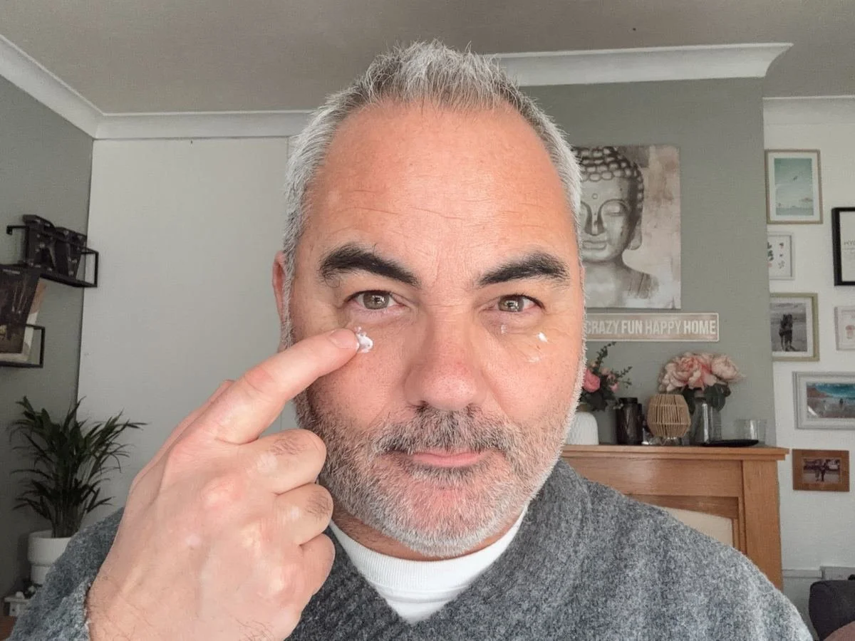 Applying eye cream under the eyes as part of a men's skincare routine