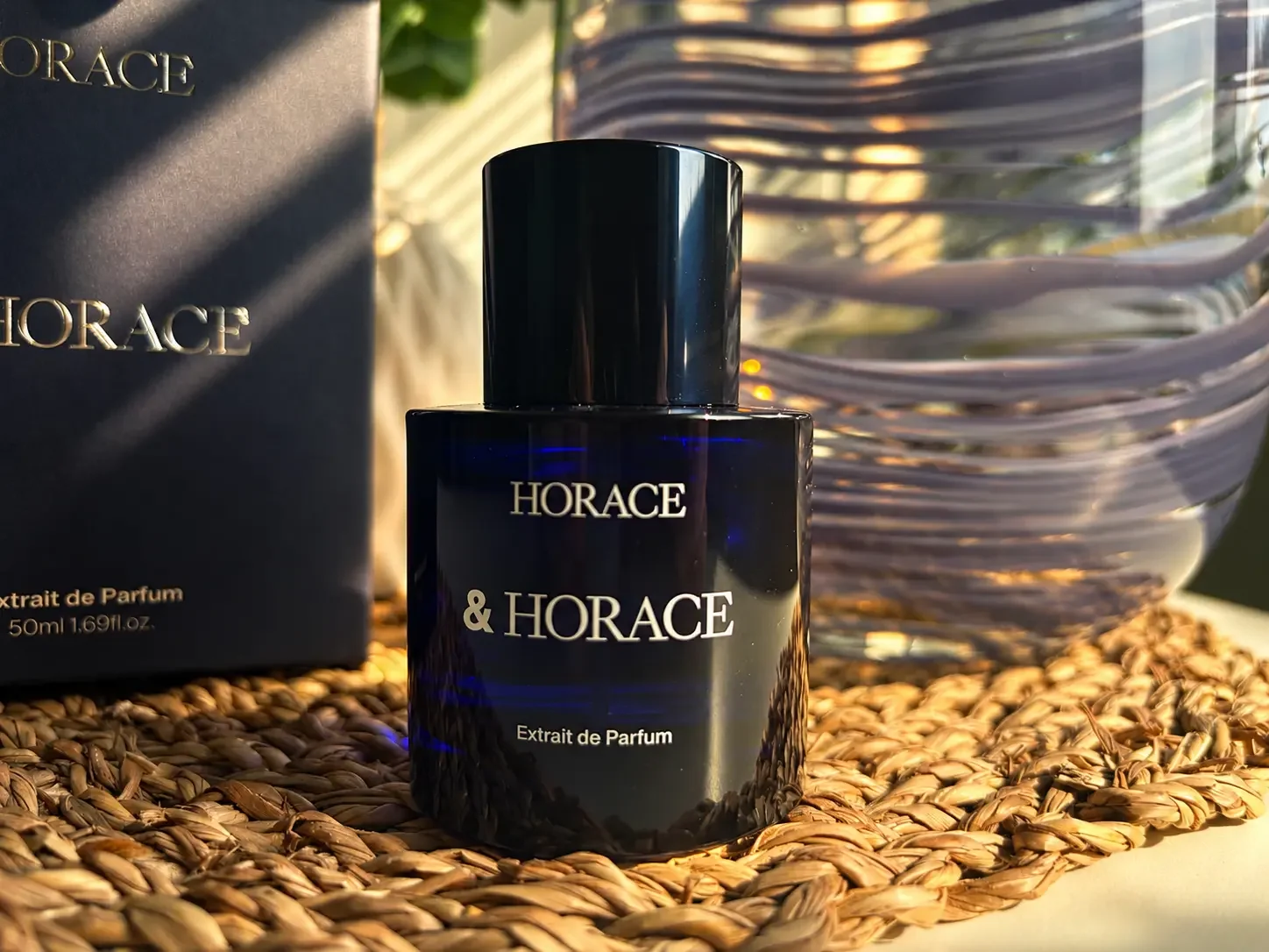 Horace Extrait de Parfum bottle photographed indoors in warm natural light beside its box and a textured glass vase.