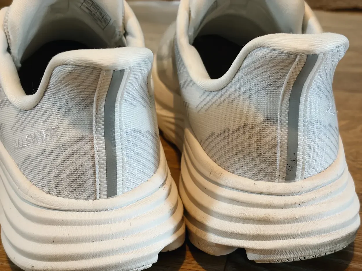 Rear view of white Allswifit ActiveSolid trainers showing the padded heel collars, pull tabs and layered cushioned soles.