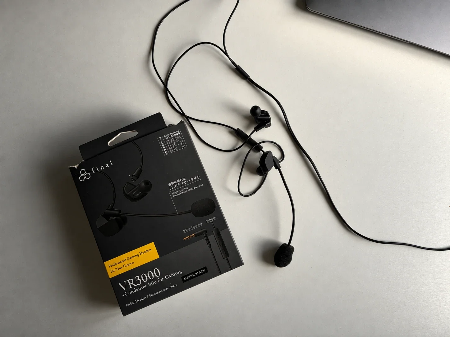 Final VR3000 gaming earphones with condenser microphone displayed beside the retail box on a white desk.