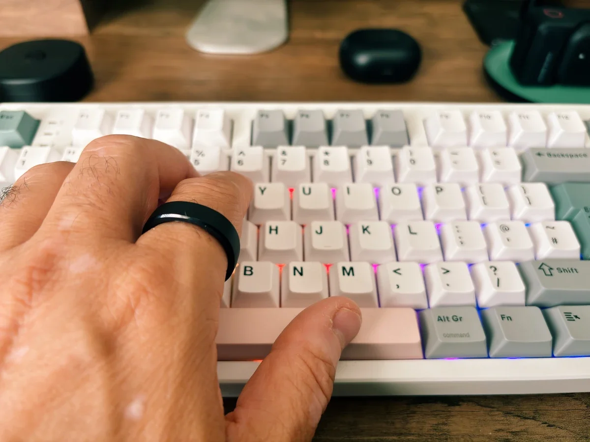 Hands typing on the Epomaker TH87 mechanical keyboard with RGB lighting visible between the keys.
