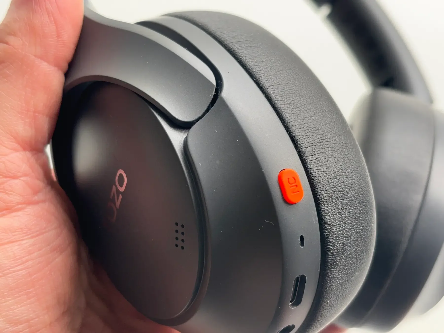 Close-up detail of the Tozo HT3 headphones showing the iconic orange ANC button, build quality, ear cup design, and controls in Jerome’s hands-on review.