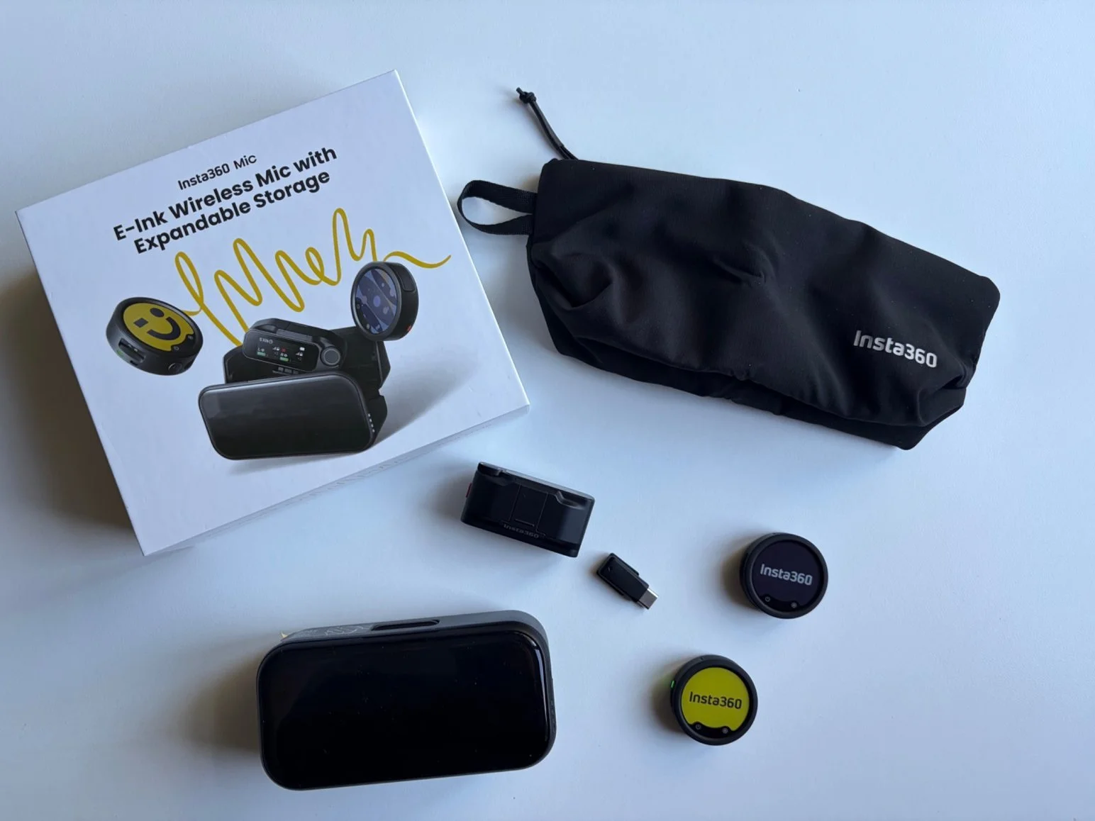 Insta360 Mic kit laid out with two transmitters, receiver, charging case, USB-C adapter and pouch.
