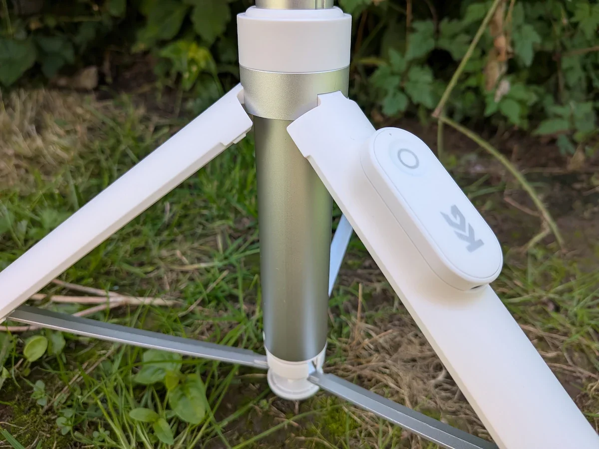 Close-up of the KraftGeek JustTap Magnetic Phone Tripod base with open legs and magnetic remote during outdoor testing.