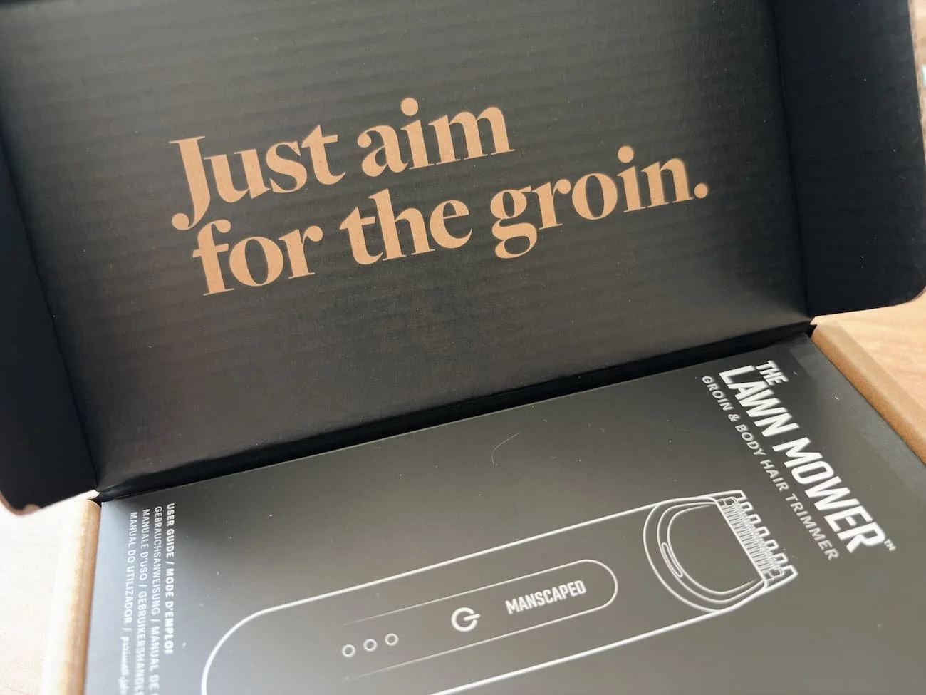 Inside the Manscaped Lawn Mower Go packaging, showing the “Just aim for the groin” message and product user guide.