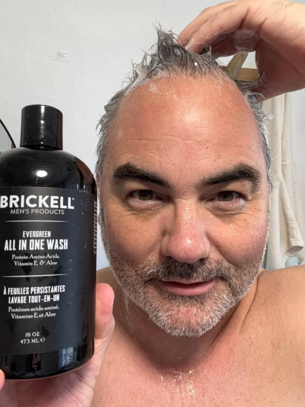 Jerome using Brickell Evergreen All in One Wash during his hair care routine.