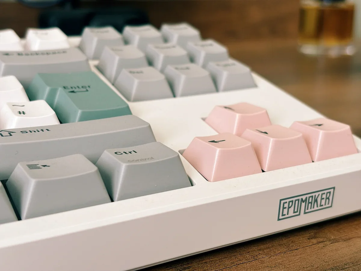 Epomaker TH87 keyboard close-up showing the pastel keycaps, arrow keys and Epomaker logo on the front edge.