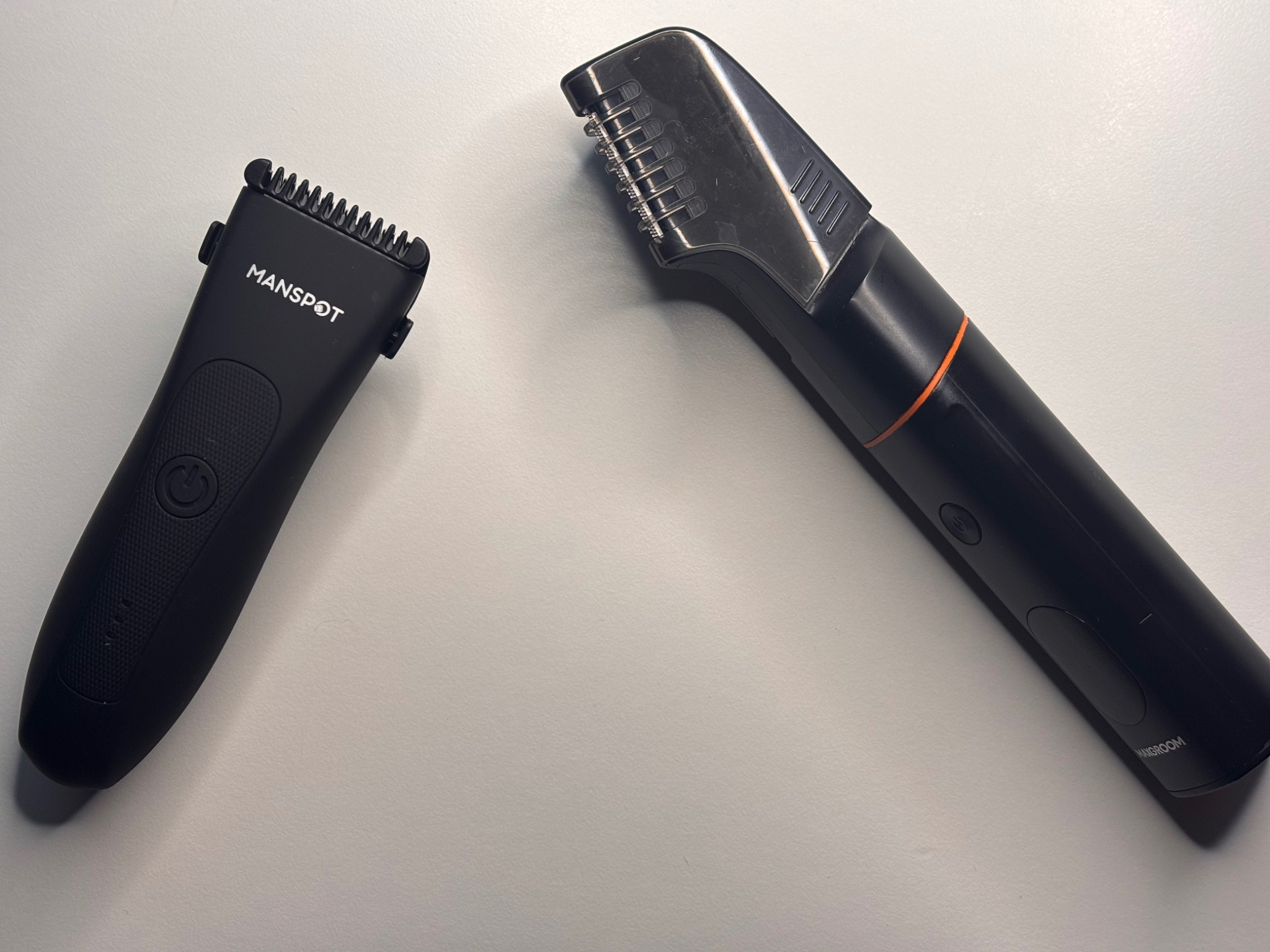 Manspot and Maxgroom body hair trimmers side by side on a table