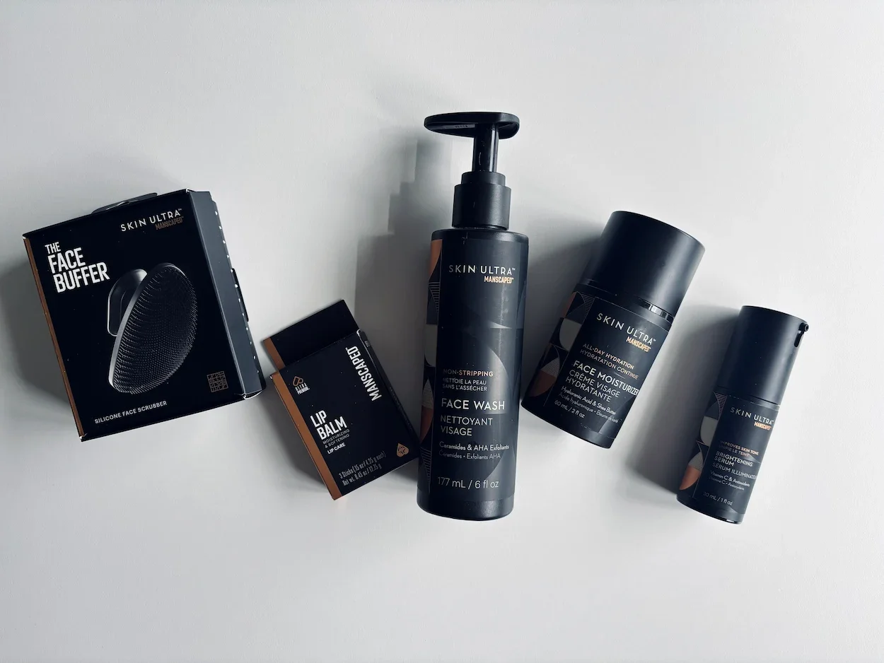 Manscaped Skin Ultra skincare products laid out on a white table, including face wash, face moisturiser, brightening serum, lip balm and The Face Buffer