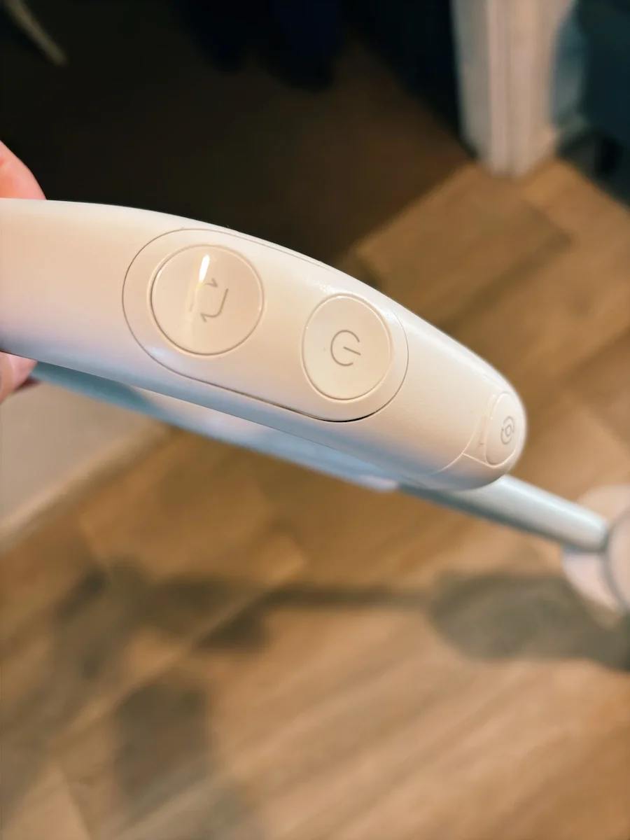 Close-up of the Roborock F25 GT handle controls showing the power and cleaning mode buttons.