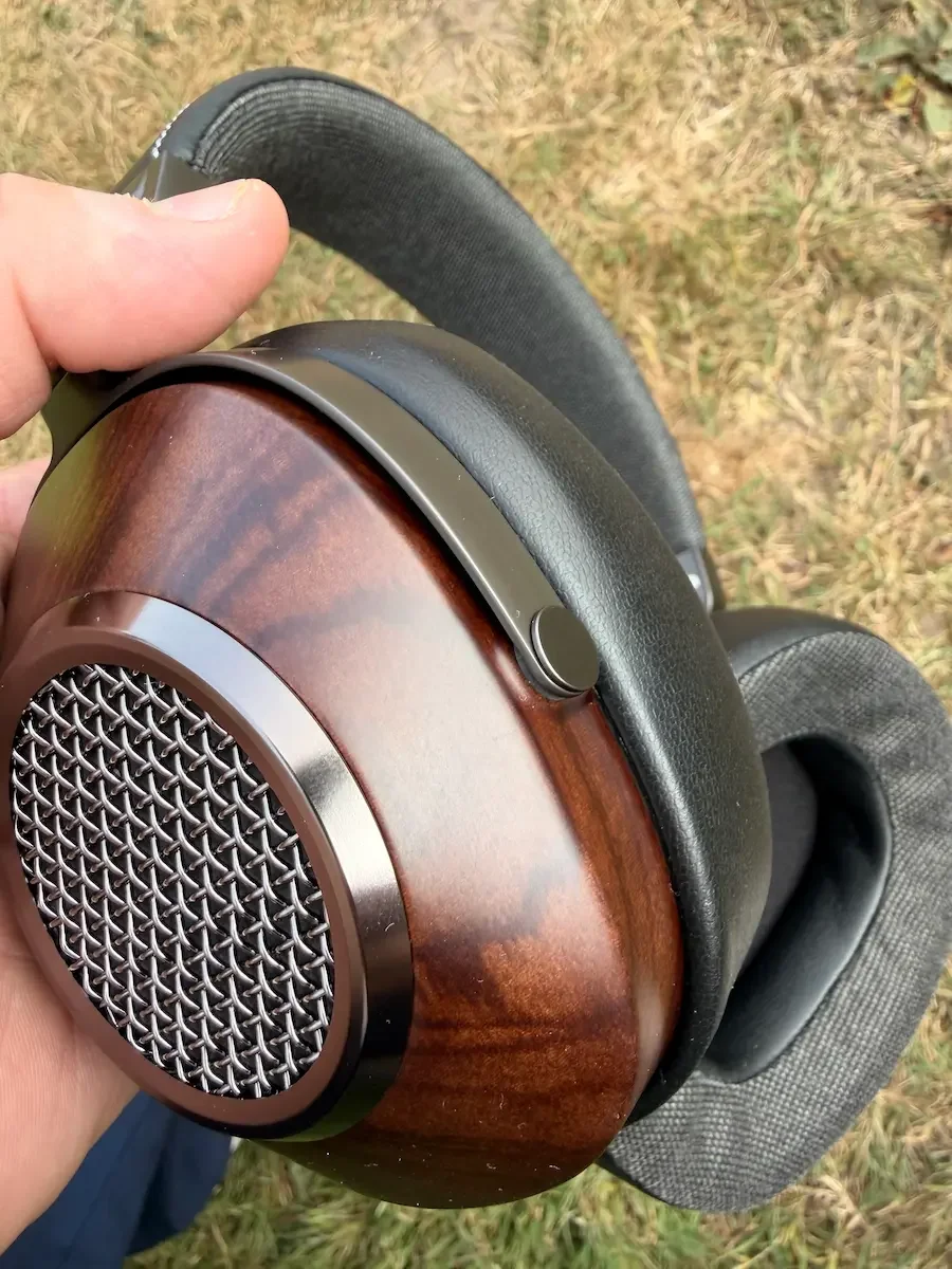 Detailed view of the walnut wood finish and metal grille on the SIVGA Anser headphones.