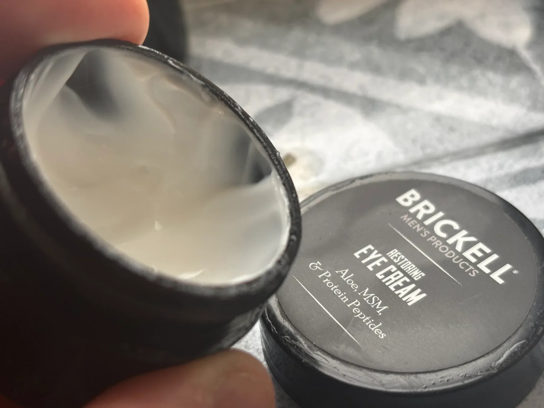 Close up of open jar showing the rich, white texture of Brickell Restoring Eye Cream for men