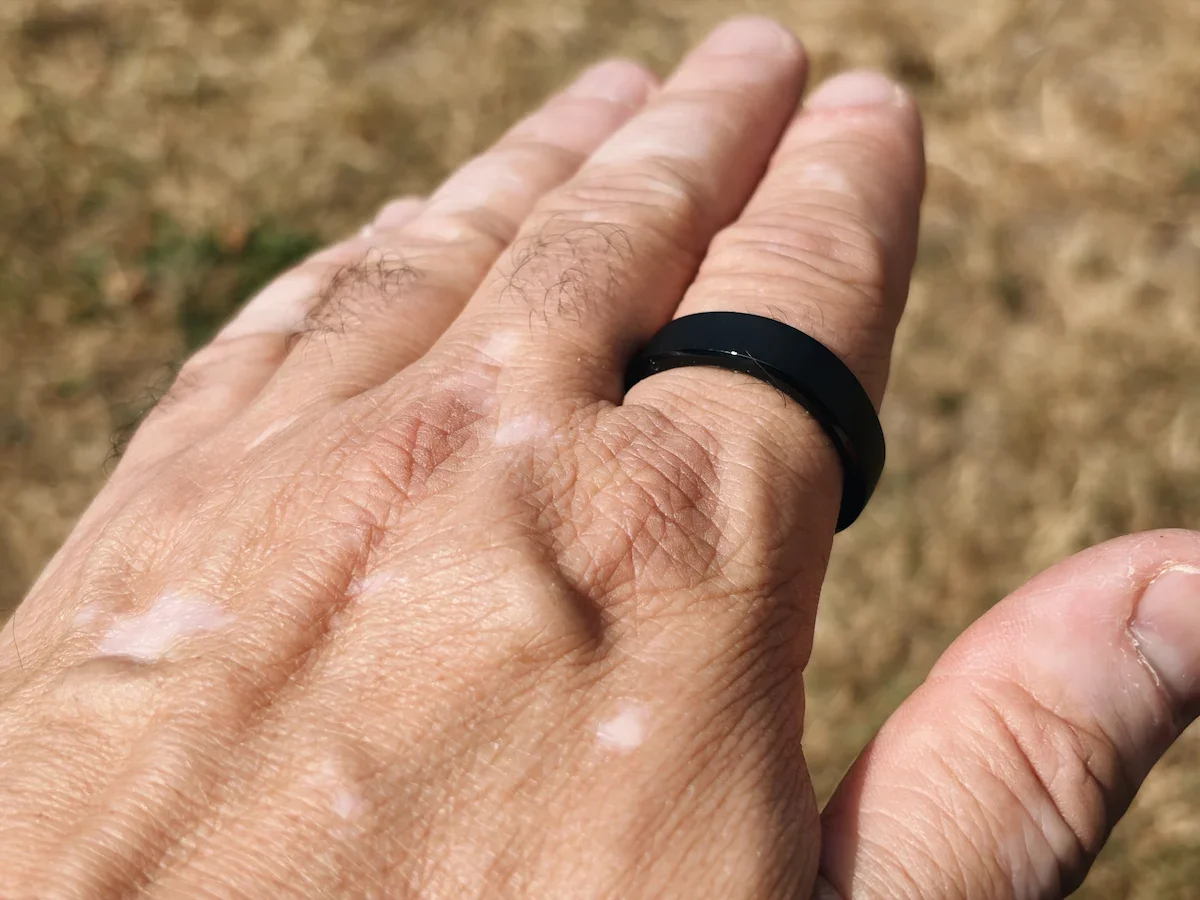 Close-up of the Matte Black RingConn Gen 3 smart ring worn on a finger outdoors.