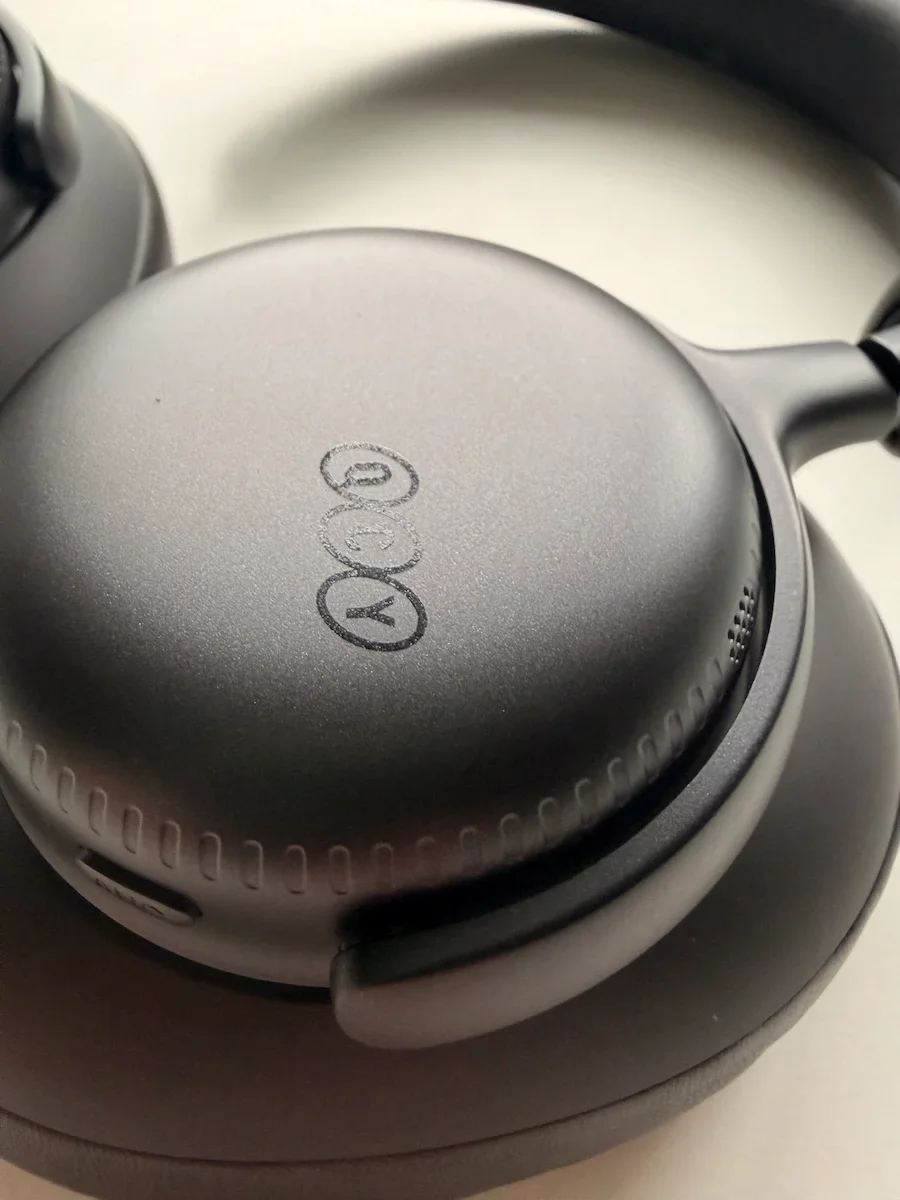 Close-up of the QCY H6 Ultra ear cup showing the physical control buttons and matte black finish