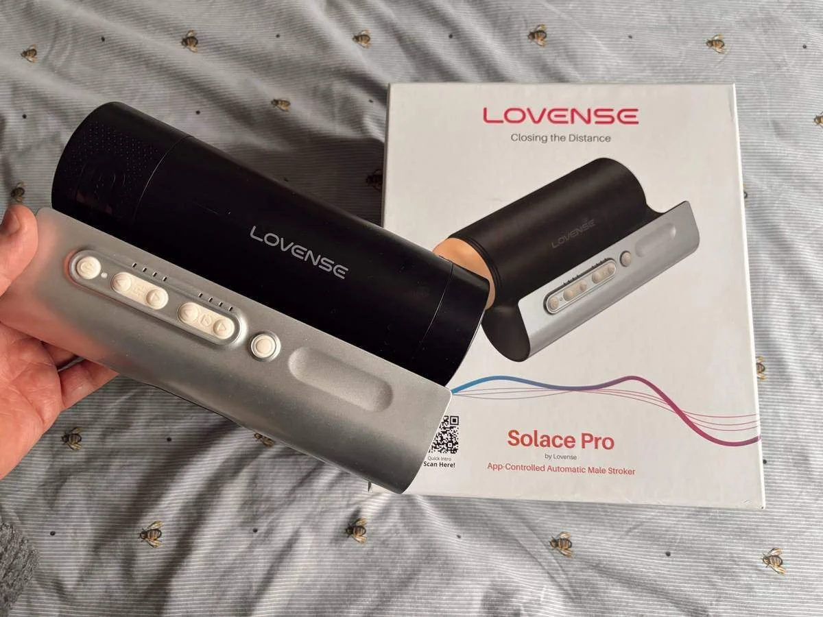 Me holding the Lovense Solace Pro on my bed