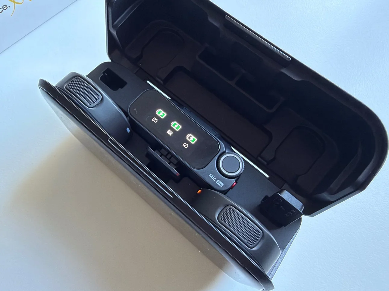 Open Insta360 Mic Pro charging case containing two transmitters and a receiver with battery indicators