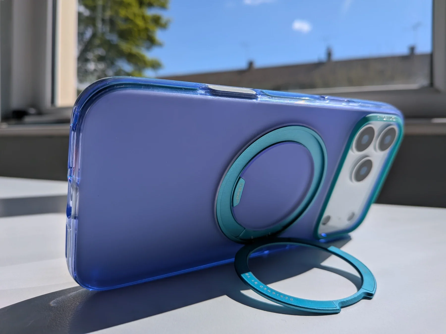 TORRAS Ostand Q3 Hue case in purple and green on the iPhone 17 Pro Max, showing the rear design and open ring stand.