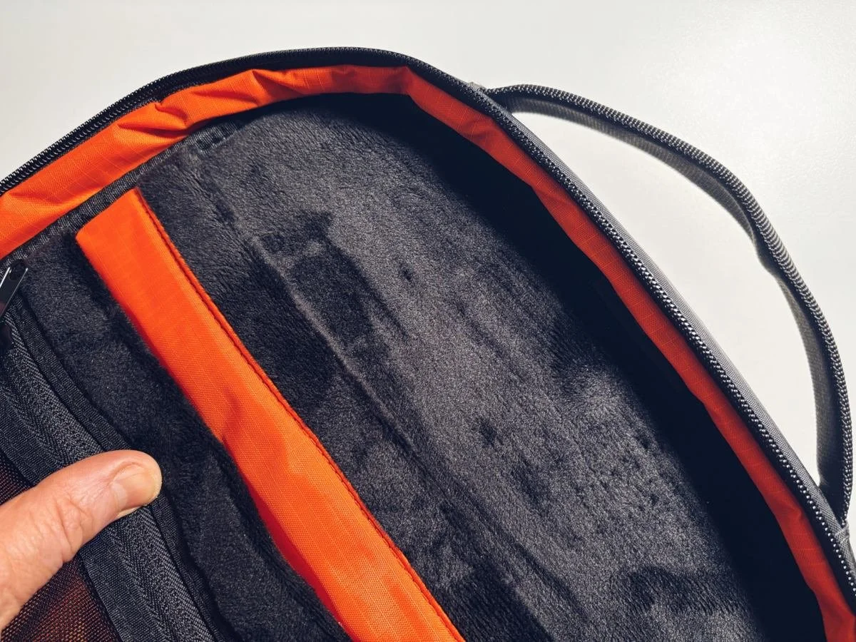 Close-up of the ADD1D D2D Essential Backpack interior showing the soft lining and high-visibility orange trim around the main compartment.