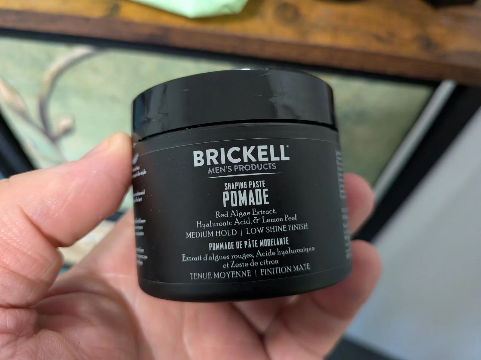 Close-up of Brickell Shaping Paste Pomade in hand, photographed by Jerome for a men’s hair styling review.