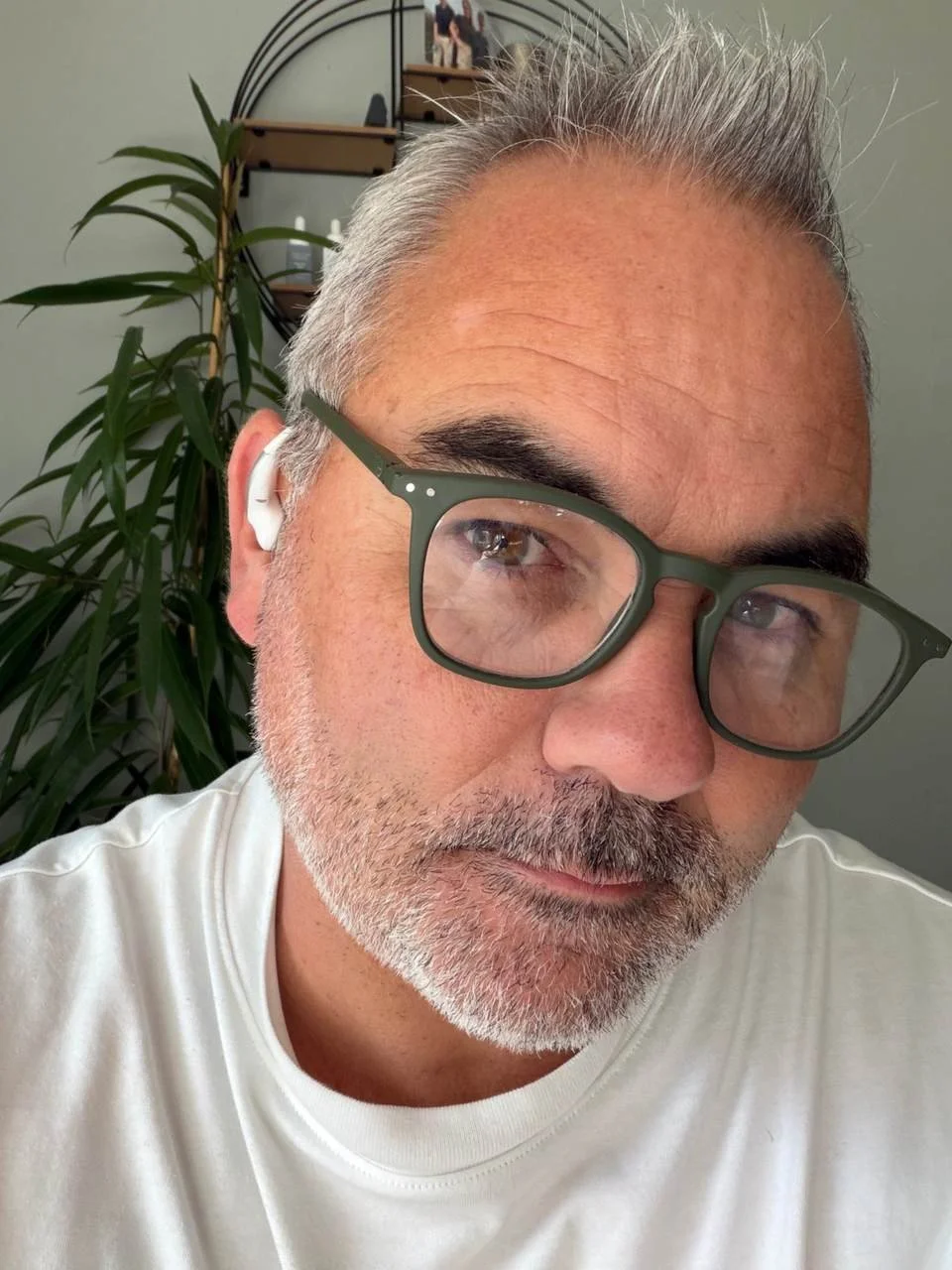Reviewer wearing a white Timekettle LiveTalk AI translation earbud with green glasses, demonstrating the open-ear fit.