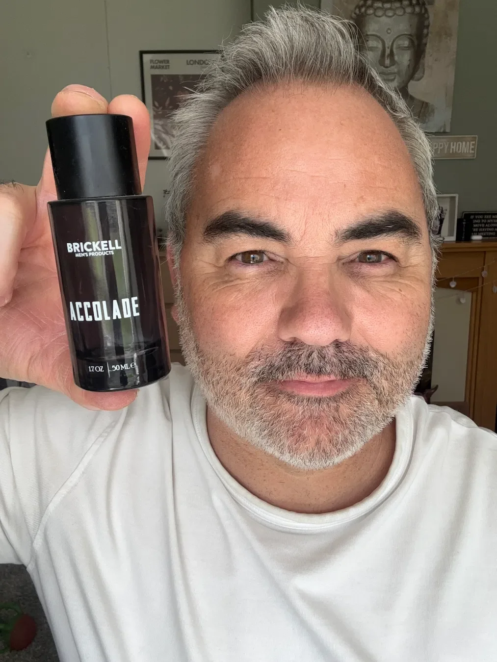 Jerome holding a bottle of Brickell Accolade cologne for his fragrance review in his living room.