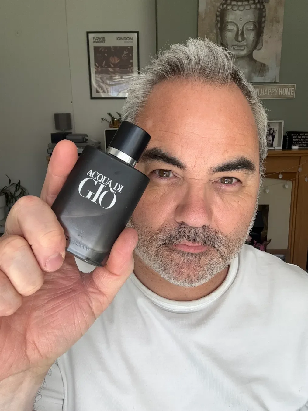 Jerome holds a bottle of Acqua di Gio Parfum by Giorgio Armani for his fragrance review in his living room.