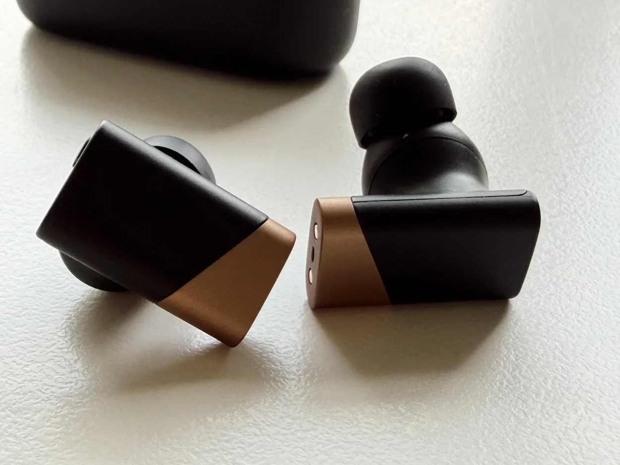 Close-up of the Status Audio GoldenSound Pro X earbuds showing the black and gold finish