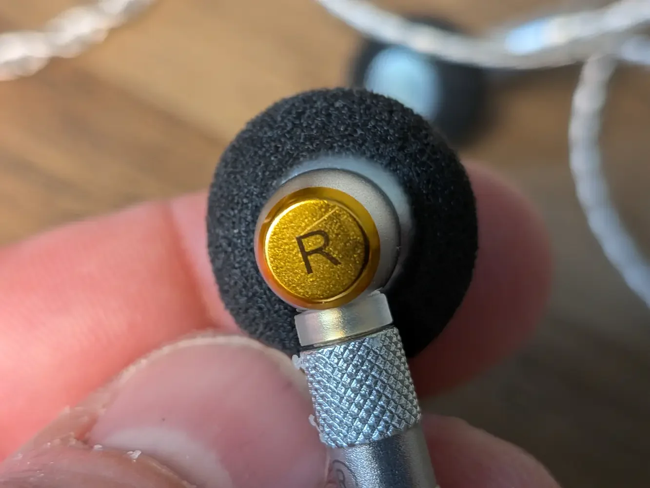 Close-up of the right SIVGA M260 earbud showing the gold R marking and textured metal connector