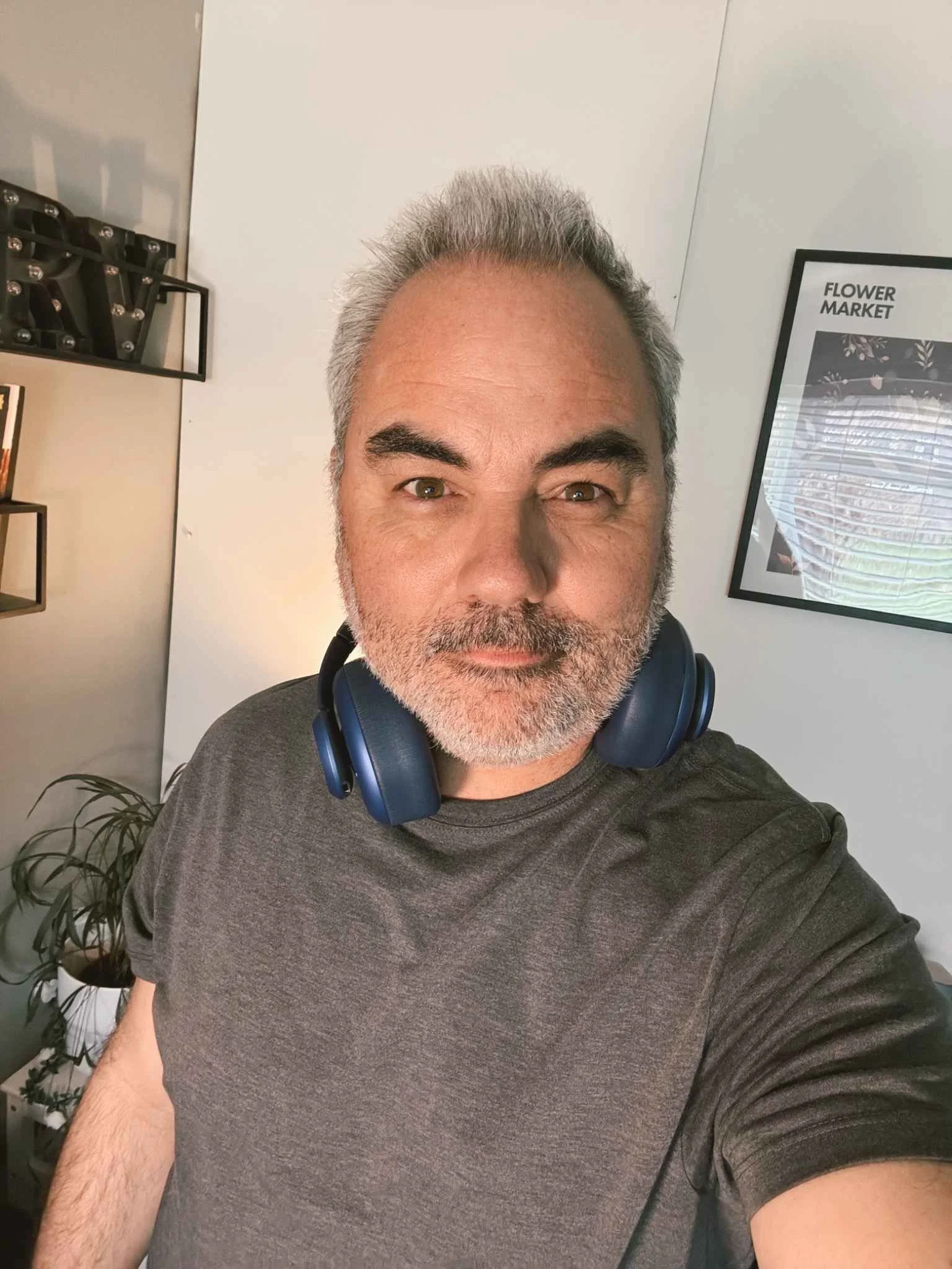Man wearing Fresh ’n Rebel Clam Ace 2 headphones around his neck, indoor portrait photo in natural light