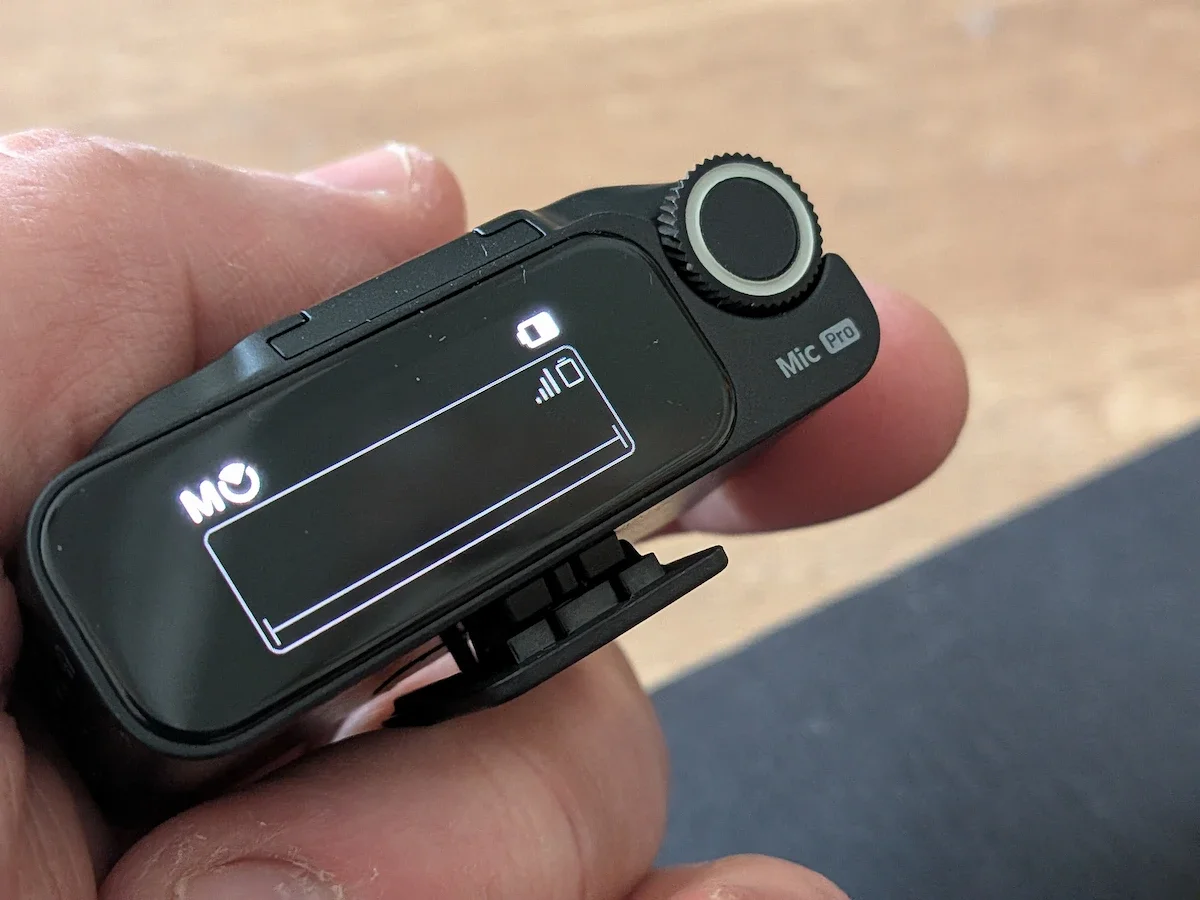Close-up of the Insta360 Mic Pro receiver showing the screen, control dial and Mic Pro branding.