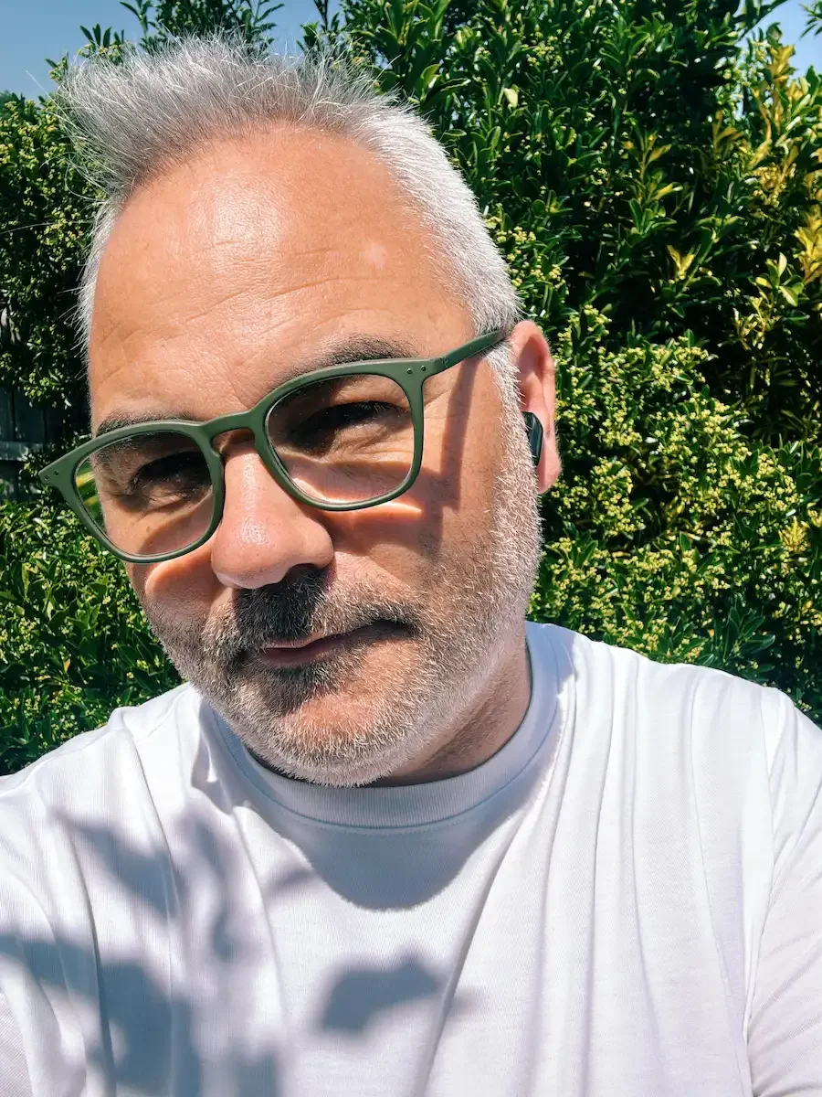 Jerome testing the SoundPEATS Air6 HS open-fit earbuds outdoors in bright sunlight.