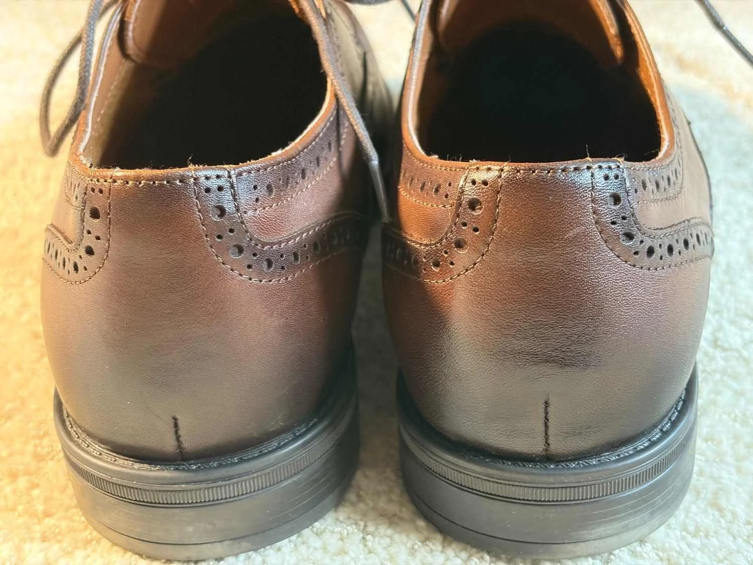 Rear view of Bruno Marc brown leather brogues showing heel stitching, decorative perforations and black rubber heels.