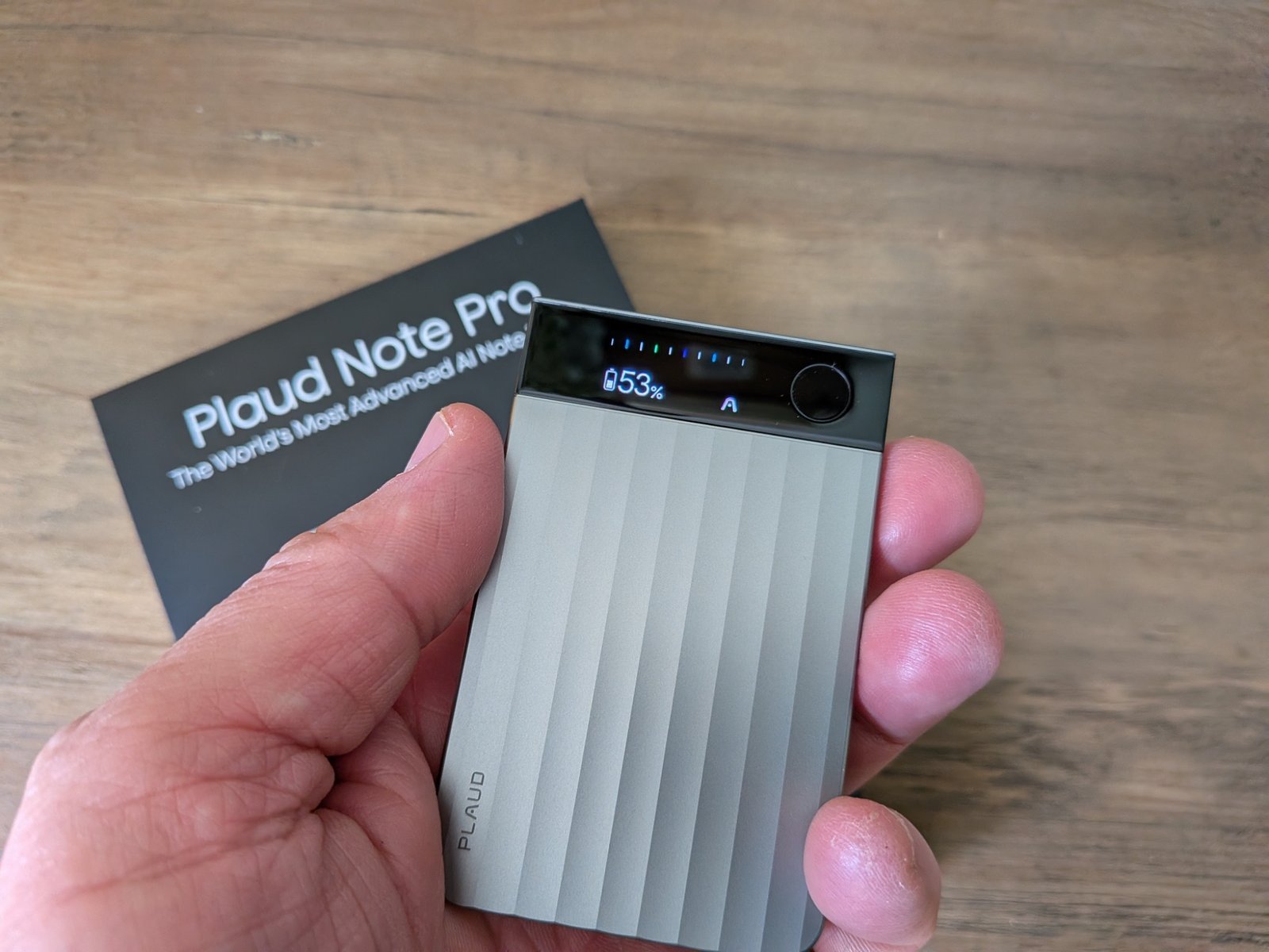 Close-up hero image of the Plaud Note Pro held in hand, showing the compact design, front display and battery level during real-world use