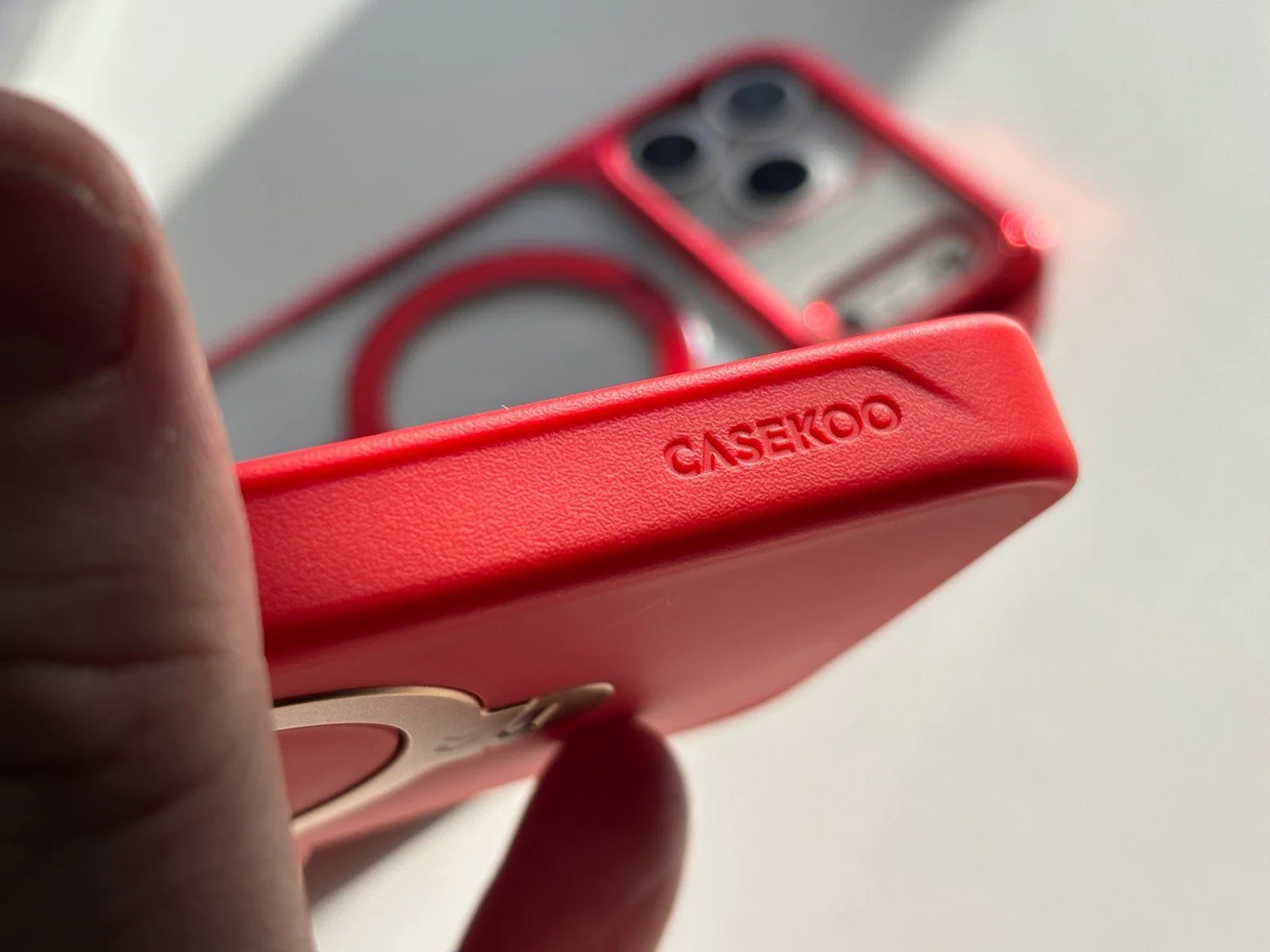 Close-up of CASEKOO branding on red textured frame of iPhone 17 Pro Max Spin Magnetic Stand Case