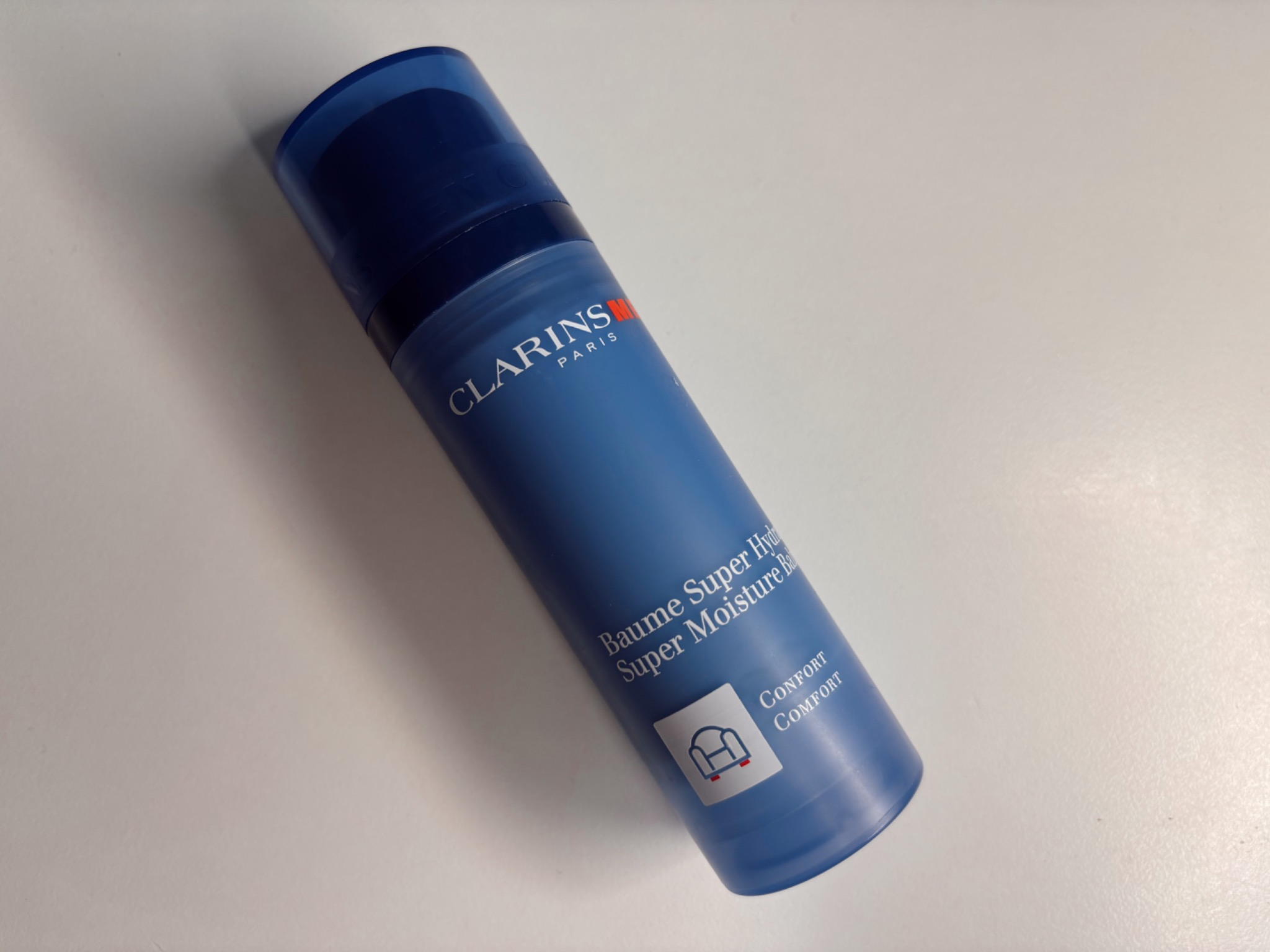 Clarins Men Super Moisture Balm packaging in blue bottle photographed on a white background, lightweight daily moisturiser for men