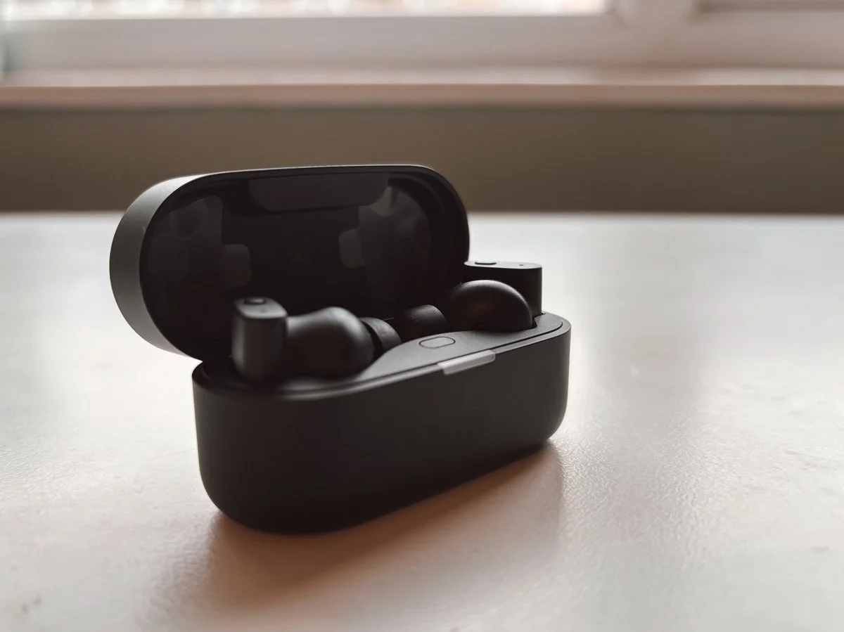 Status Pro X earbuds inside open charging case