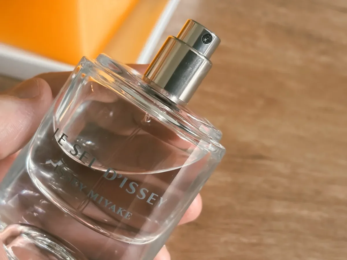 Close-up of Le Sel d’Issey by Issey Miyake fragrance spray and glass bottle in natural light