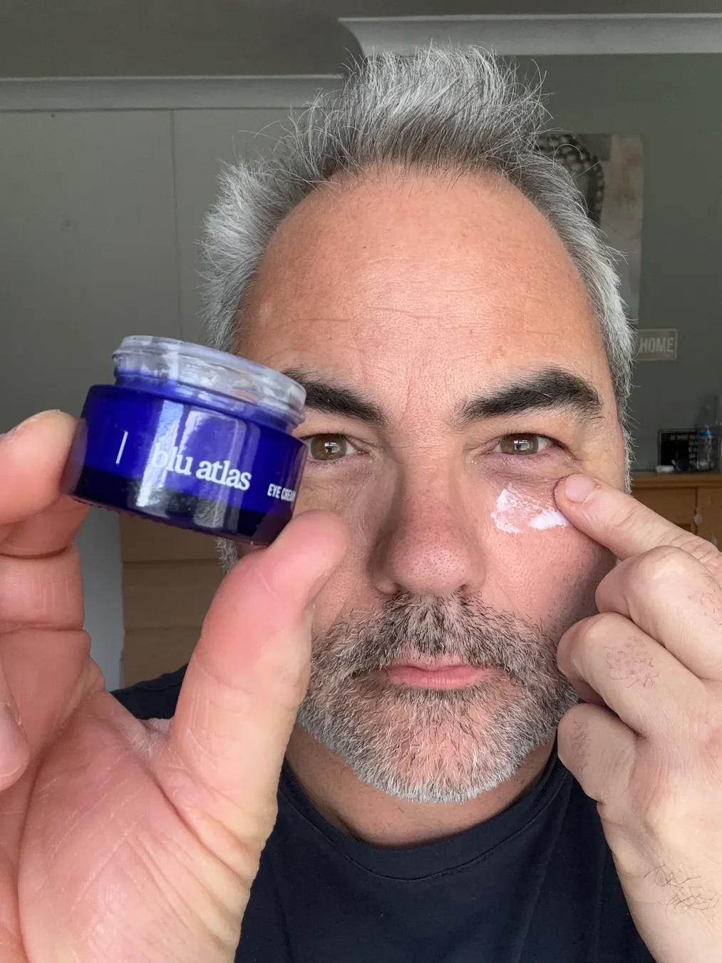 Jerome demonstrating the thick, waxy texture of Blu Atlas Brightening Eye Cream during application.