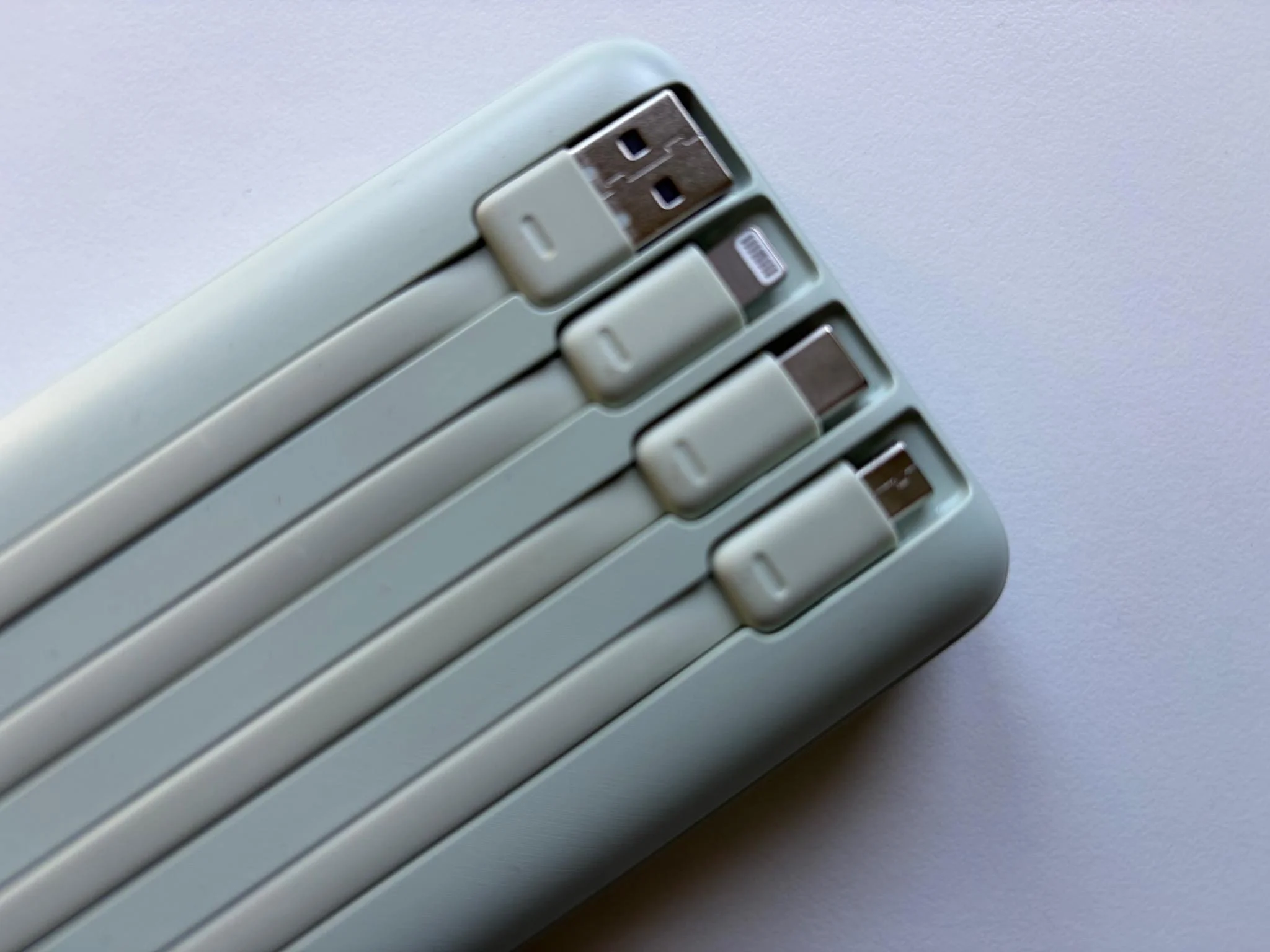 Close-up of the built-in USB-A, Lightning, USB-C and Micro-USB cables on the Charmast 20000mAh power bank.