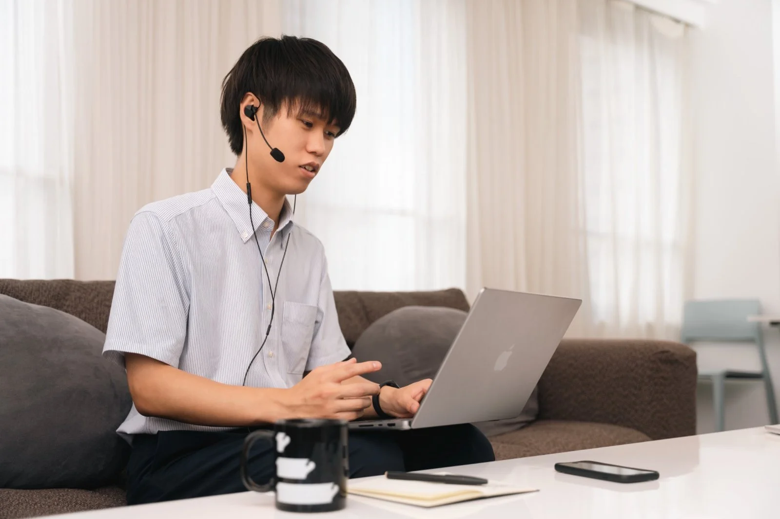 Person wearing Final VR3000 gaming earphones with condenser mic while using a laptop