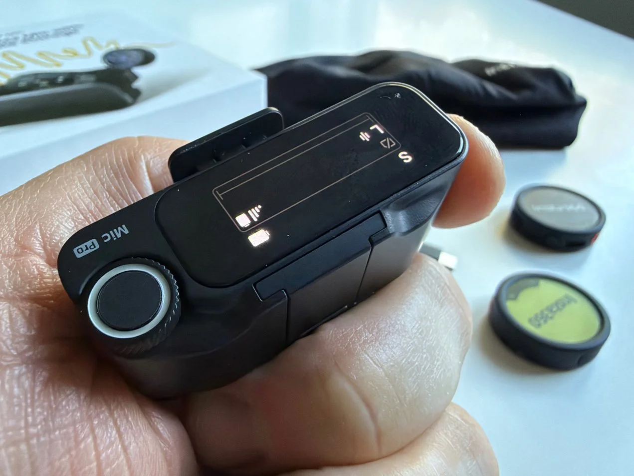 Close-up of the Insta360 Mic Pro receiver showing its screen, control dial and Mic Pro branding.